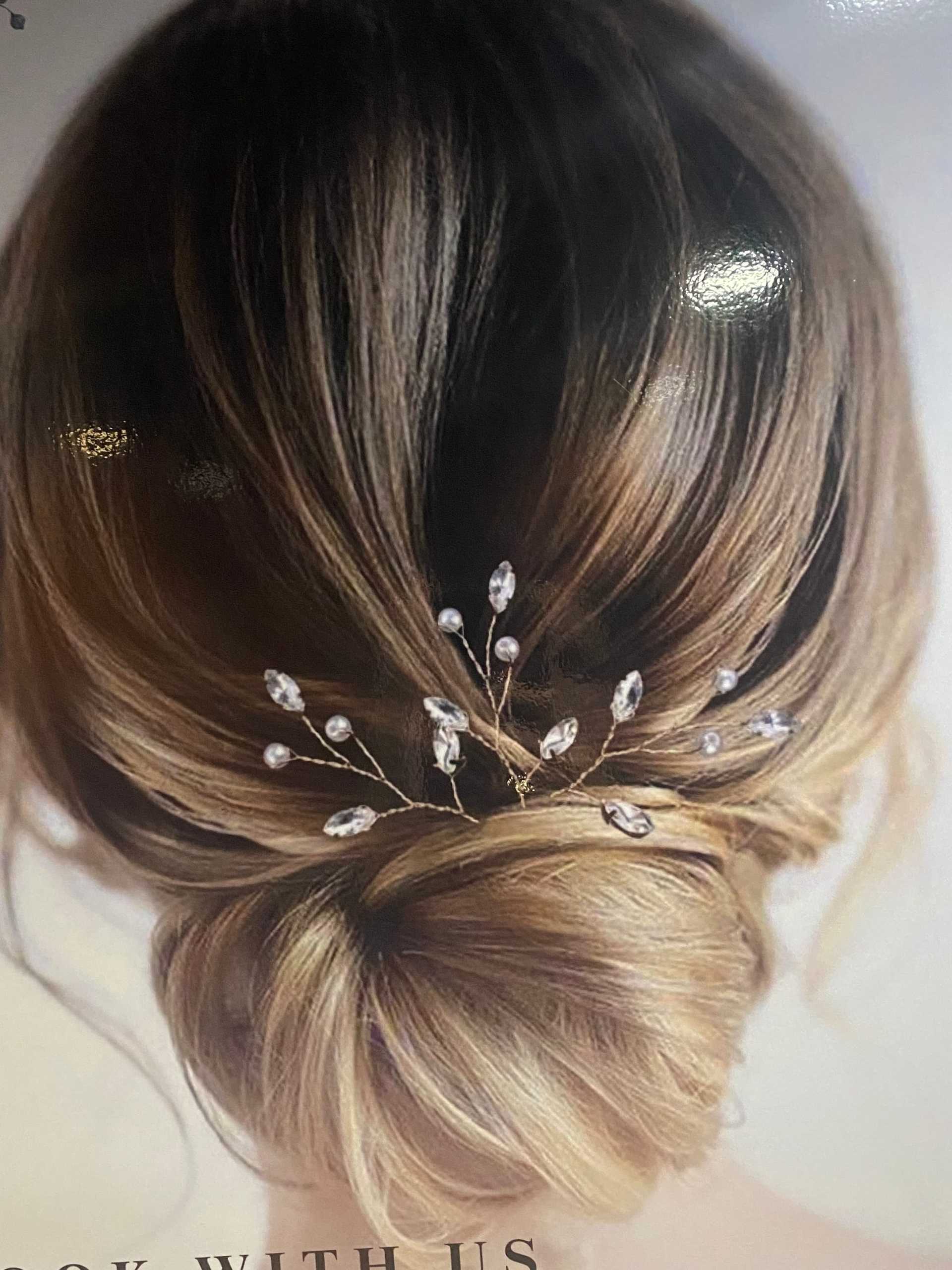 Elegant updo hairstyle adorned with delicate pearl-like hairpins.